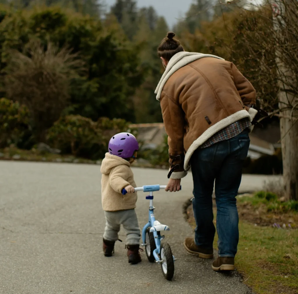 padre va de la mano con niño y una bicicleta de equilibrio