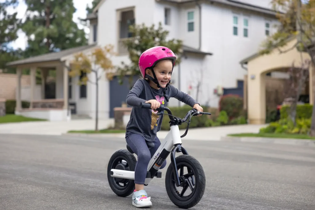 niña con casco montando bicicleta de equilibrio 